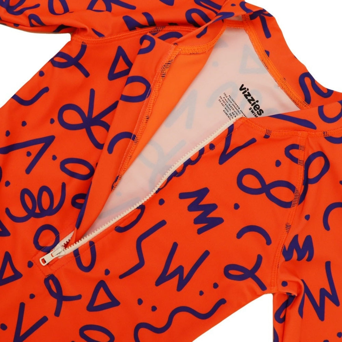 Close-up of a Vizzies Swim girls one-piece frill swimsuit in bright squiggle pop pattern, showing the front zipper and printed tag details.