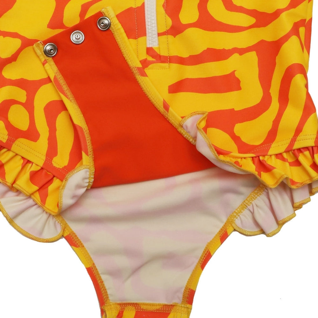 Close-up of a Vizzies Swim girls one-piece frill swimsuit in bright sunburst pattern, showing the crotch snaps and ruffle details. 