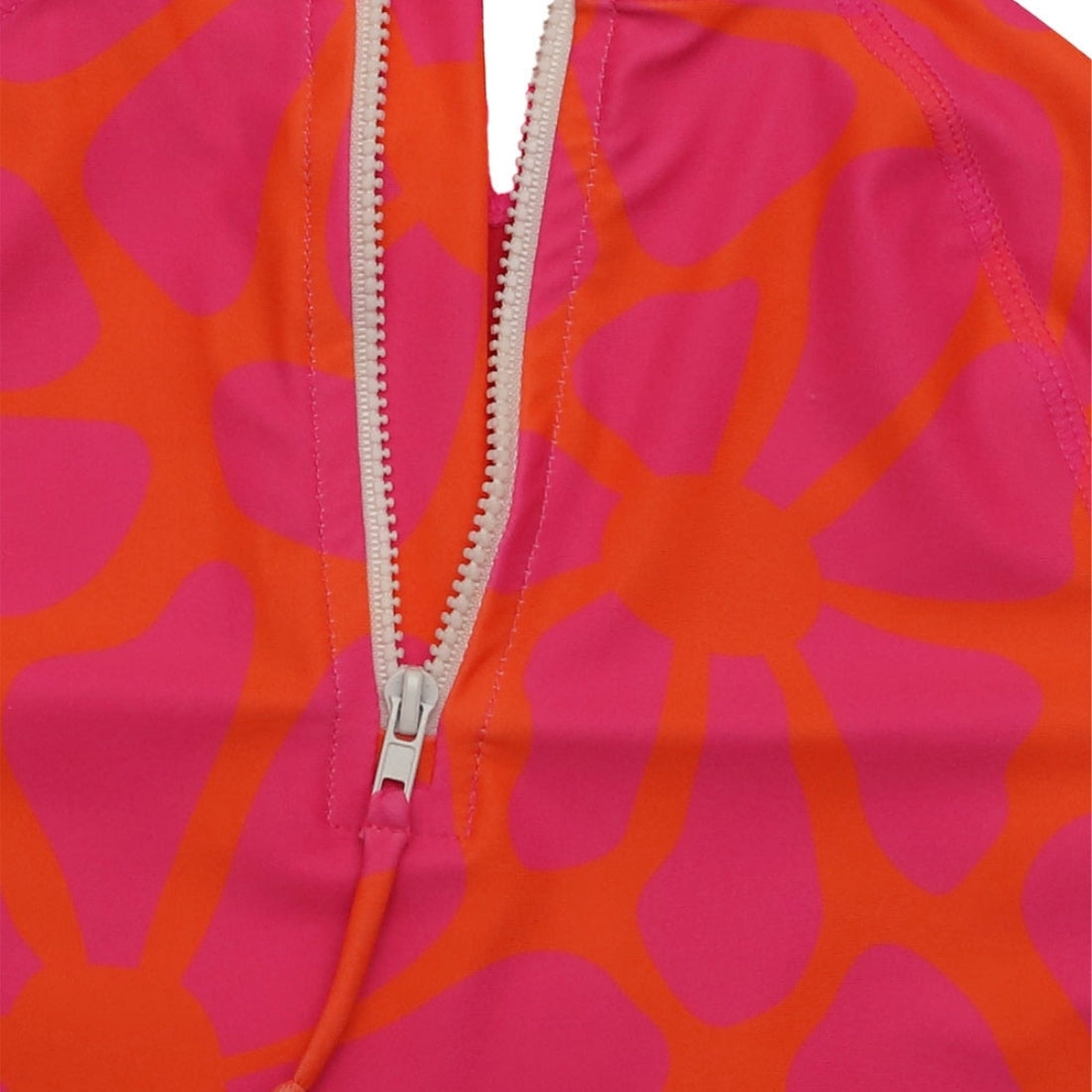 Close-up of a bright tangy blossom print kids swim rashie with a white zipper running vertically down the centre.